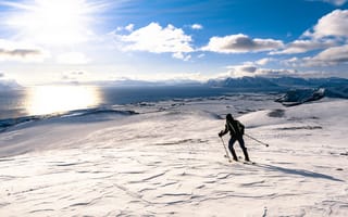 Картинка Лыжник едет по снегу под ярким солнцем у воды