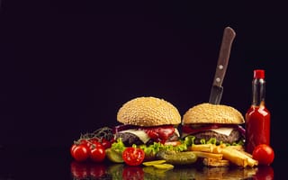 Картинка Два гамбургера на столе с ножом, овощами и кетчупом
