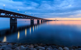 Картинка мост, пролив, небо, камни, закат, вечер, фонари, пейзаж, облака, тучи, берег, огни, Швеция