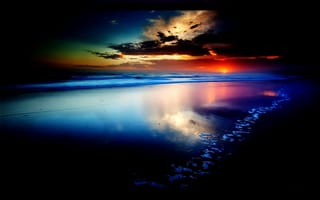 Картинка Багряный закат с заходящим за линию горизонта солнцем, ярким свечением облаков различными красками, над океанским побережьем с красивым ярко-синим отливом воды