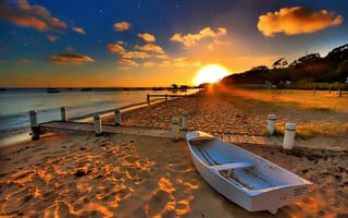 Картинка Белая лодка на пляже под закатным солнцем