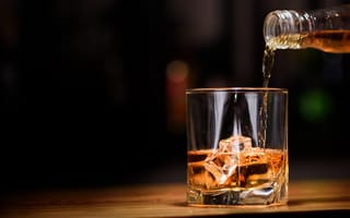 Картинка Виски наливают из бутылки в стакан со льдом