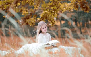 Картинка Улыбающаяся девочка в белом платье читает книгу