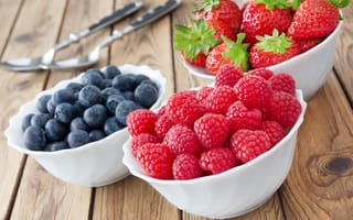 Картинка Свежие ягоды малины, клубники и черники в белых тарелках на столе