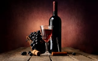 Картинка Бутылка красного вина на столе с бокалом и синим виноградом