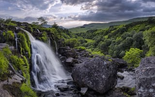 Картинка Водопад стекает по камням на фоне красивого неба и зеленого леса
