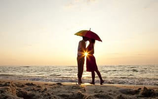 Картинка Влюбленная пара на пляже стоит под зонтом на закате
