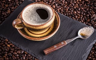 Картинка Большая чашка кофе с чайной ложкой стоят на кофейных зернах
