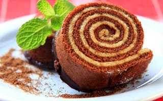 Картинка Кусок сладкого рулета с шоколадом и листом мяты на тарелке