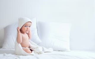 Картинка Грудной ребенок сидит на кровати с подушками