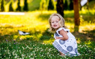 Картинка Маленькая девочка в красивом платье сидит на зеленой траве