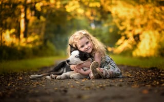 Картинка Маленькая девочка обнимает собаку на дороге осенью