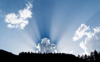 Картинка Лучи солнца пробиваются сквозь белые облака в голубом небе