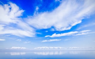Картинка Красивые белые облака над водой около заснеженных гор