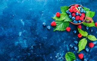 Обои Чашка с ягодами черники и малины на синем столе