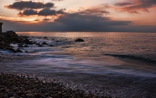 Обои Мелкие камни на берегу моря на закате
