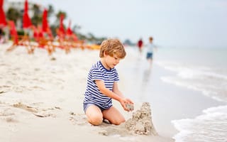 Обои Маленький мальчик строит замок из песка на пляже