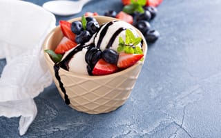 Картинка Шарики мороженого в стакане на столе с клубникой и ягодами черники