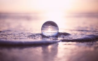 Картинка Прозрачный стеклянный шар лежит на пене в море