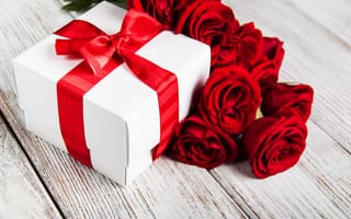 Обои Красные розы на столе с подарком с красной лентой
