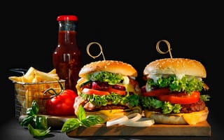 Картинка Два гамбургера на столе с картофелем фри, кетчупом и помидорами