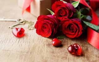 Обои Три красивые красные розы на столе с сердечками и ключами