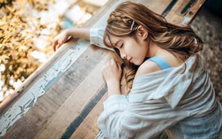 Картинка Девушка азиатка спит на деревянном столе