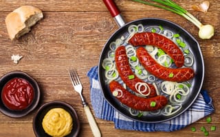 Картинка Колбаски барбекю с луком на сковороде на столе с соусом