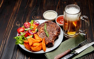 Картинка Кусок мяса на тарелке с картофелем и салатом на столе с соусом и пивом