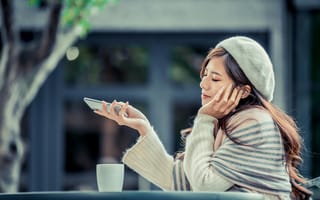 Картинка Мечтательная девушка с телефоном сидит в кафе