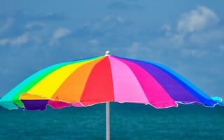 Картинка Большой разноцветный пляжный зонт на фоне моря