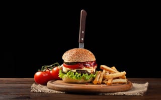 Картинка Гамбургер с ножом на столе с помидорами и картофелем фри
