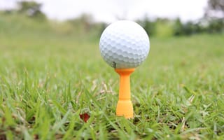 Картинка Мячик для гольфа на поле с зеленой травой