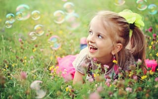 Картинка Веселая девочка лежит на траве с мыльными пузырями