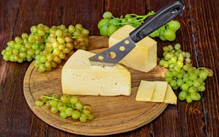 Обои Кусок твердого сыра на столе с ножом и белым виноградом