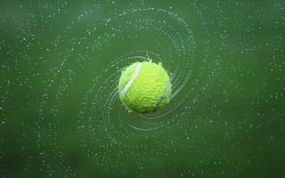 Картинка Теннисный мяч в брызгах воды на зеленом фоне