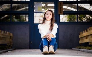Картинка Девушка азиатка в белом свитере видит на полу