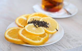 Картинка Нарезанный апельсин и лимон на тарелке с гвоздикой