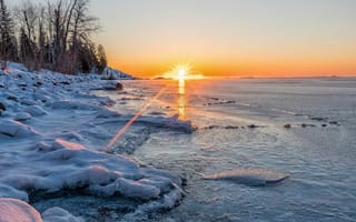 Картинка Яркое солнце освещает покрытые снегом берега реки