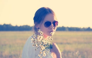 Обои Молодая девушка в солнечных очках с букетом ромашек на поле