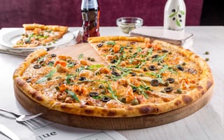 Картинка Большая аппетитная пицца с маслинами на столе в кафе