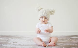 Картинка Маленький грудной ребенок в боди с шапкой на голове