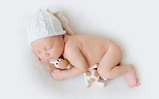 Картинка Младенец в шапке с игрушкой на белом фоне