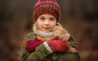 Картинка Маленькая девочка в теплой шапке и варежках с игрушкой в руках