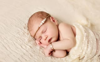Картинка Спящий грудной ребенок с украшением с жемчугом на голове