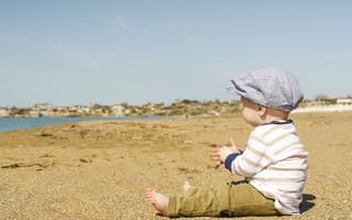 Картинка Маленький мальчик сидит на песке у реки