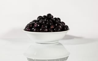 Обои Черные оливки в белой тарелке отражаются в поверхности