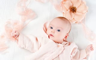 Картинка Удивленный новорожденный ребенок с цветком