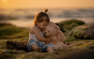 Картинка Маленькая девочка с игрушечным медведем сидит на камне