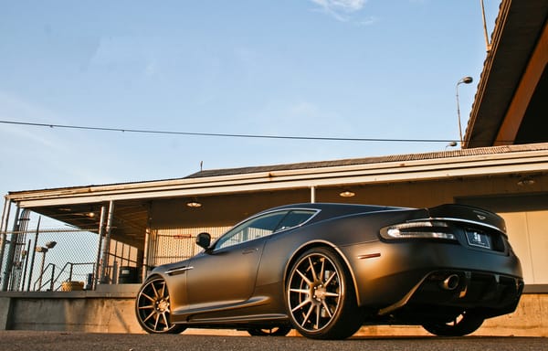 Обои Aston Martin, ограждение, чёрный, матовый, ДБС, DBS, вид сзади, Астон Мартин, здание, matte black